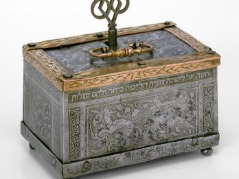 Metal box engraved with images of dogs and foliage, with handle and key on top. 