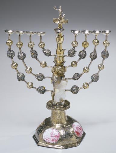 Silver candelabrum with eight branches and a central branch with carved figure on top, and decorative beads on each branch. 
