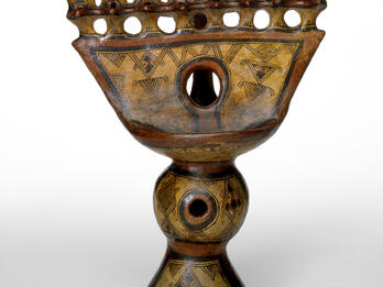 Oil lamp with geometric carvings.