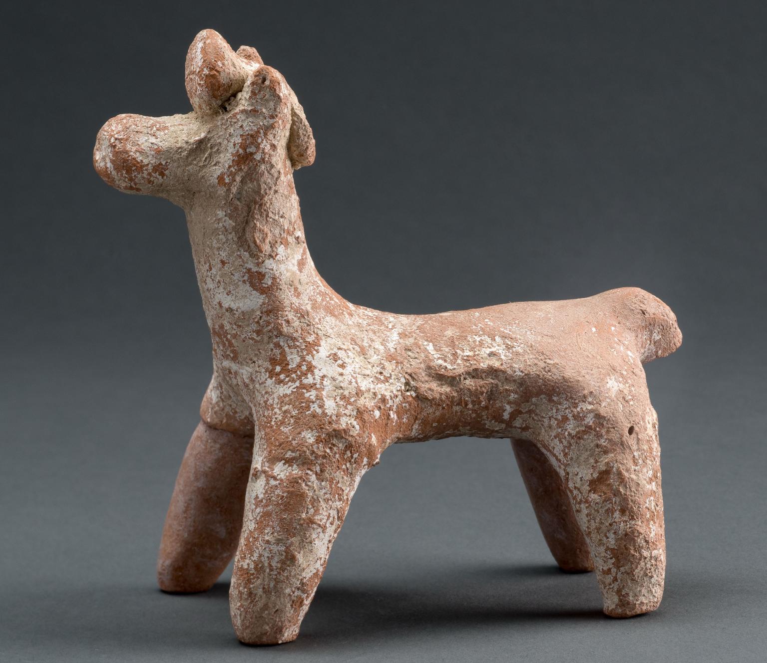 Terra-cotta figurine of horse with ornament on head.