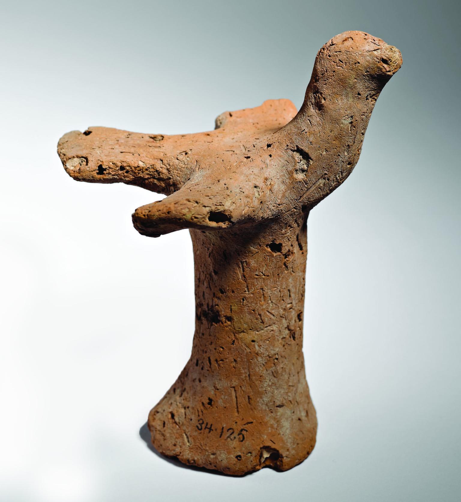 Terra-cotta bird figurine with outstretched wings on pillar.