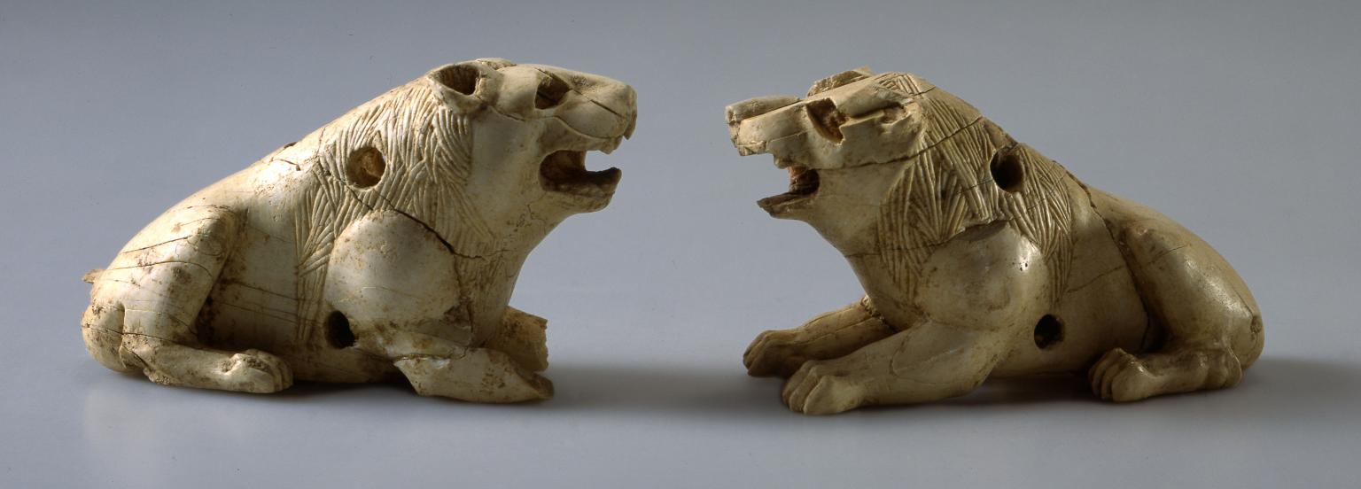 Two ivory lion figurines with open mouths and small holes throughout.