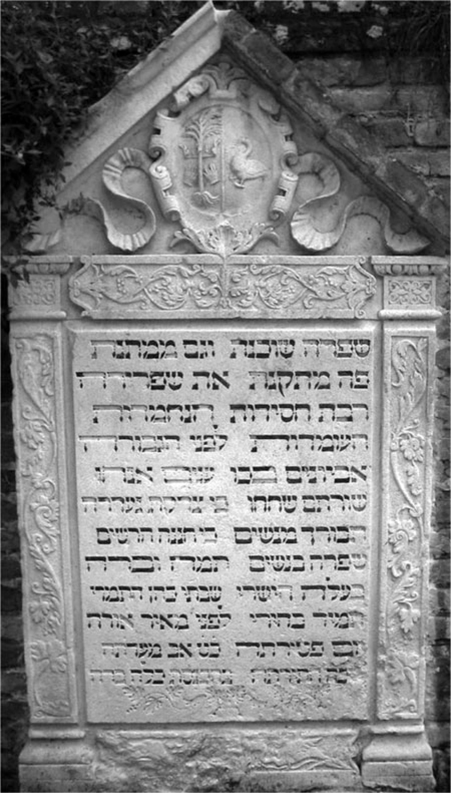 Tombstone of decorative foliage surrounding Hebrew inscription.