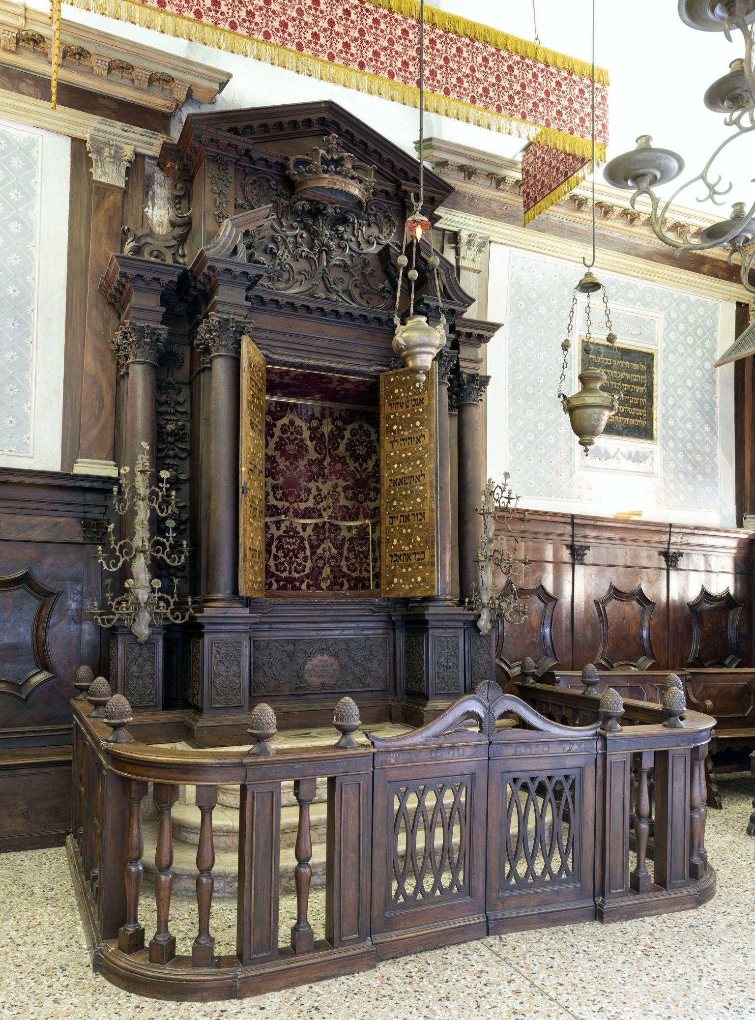 Photograph of carved Torah ark with gold doors, crown at top, and wooden fence around it.
