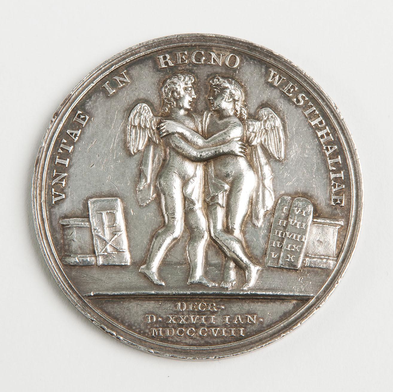 Medal featuring two angels embracing and Latin text around. 