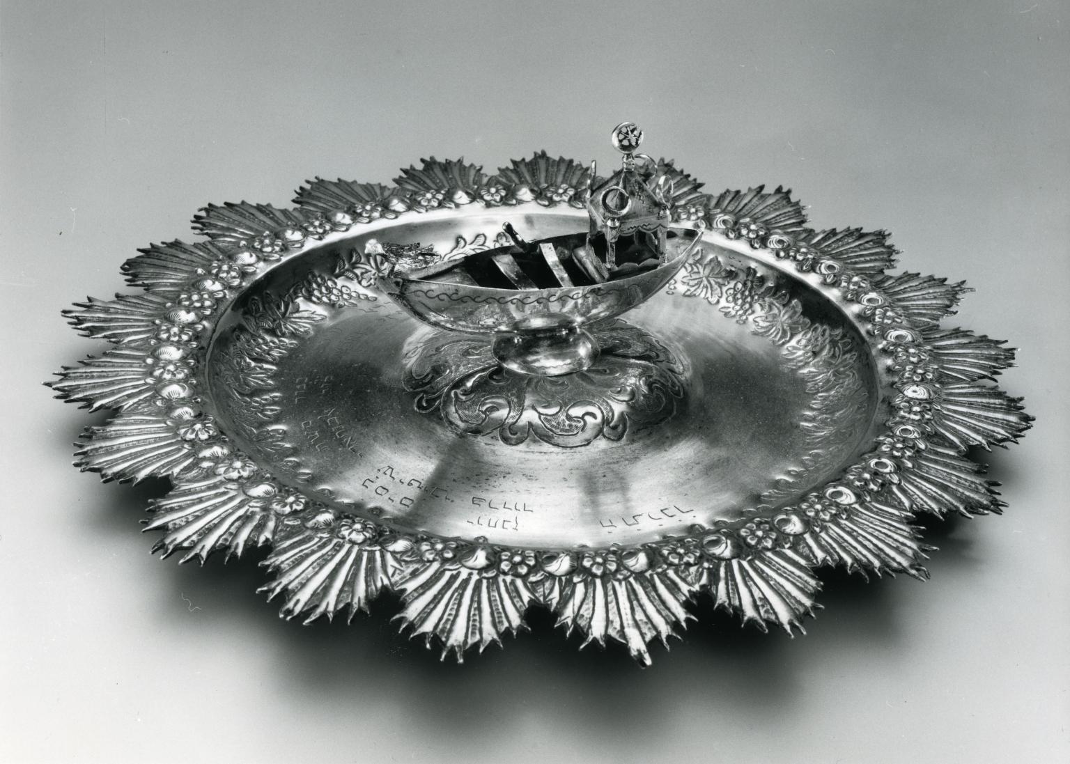 Silver plate featuring a boat in the center. 