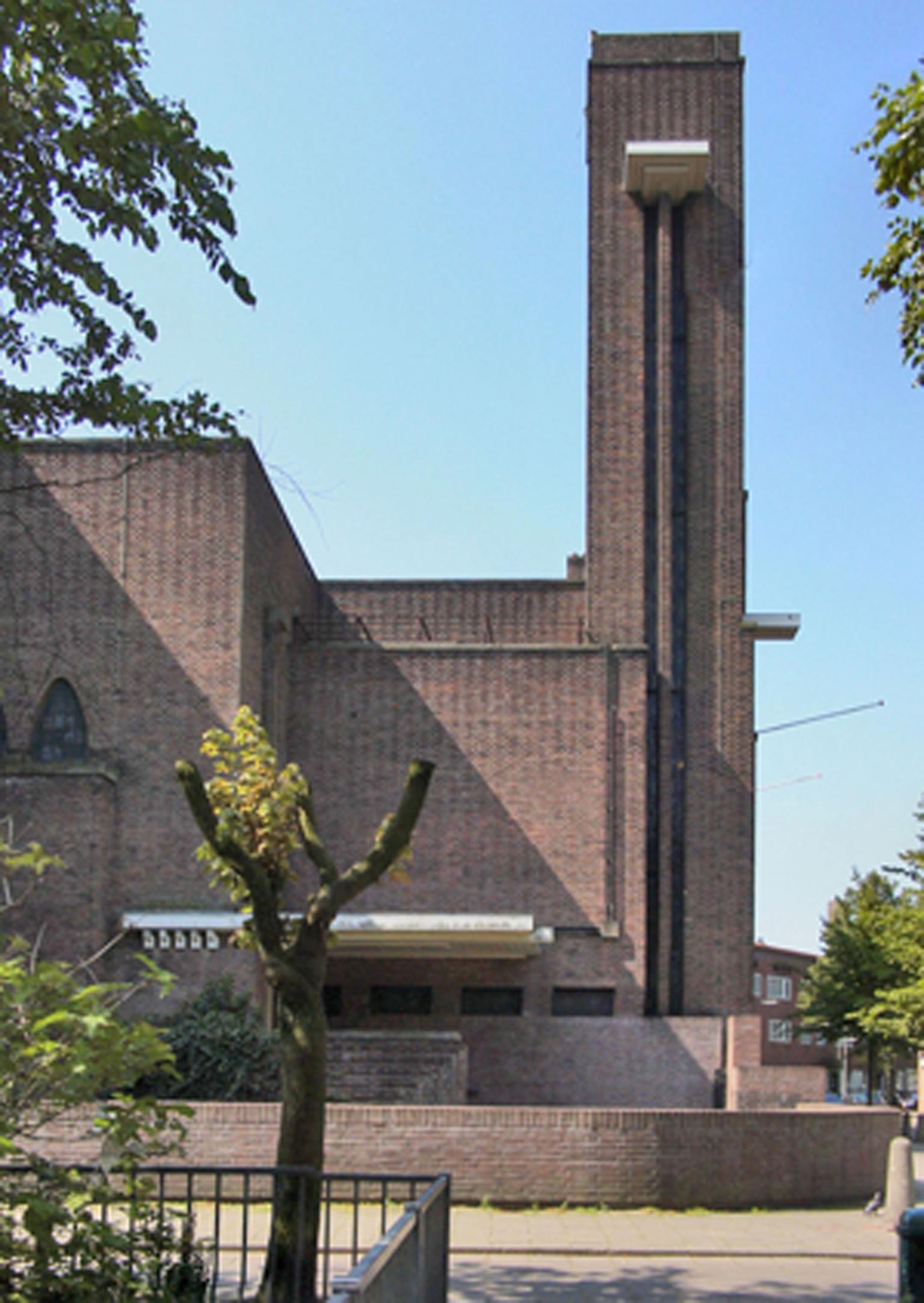 Photograph of brick facade and block shaped tower of building.