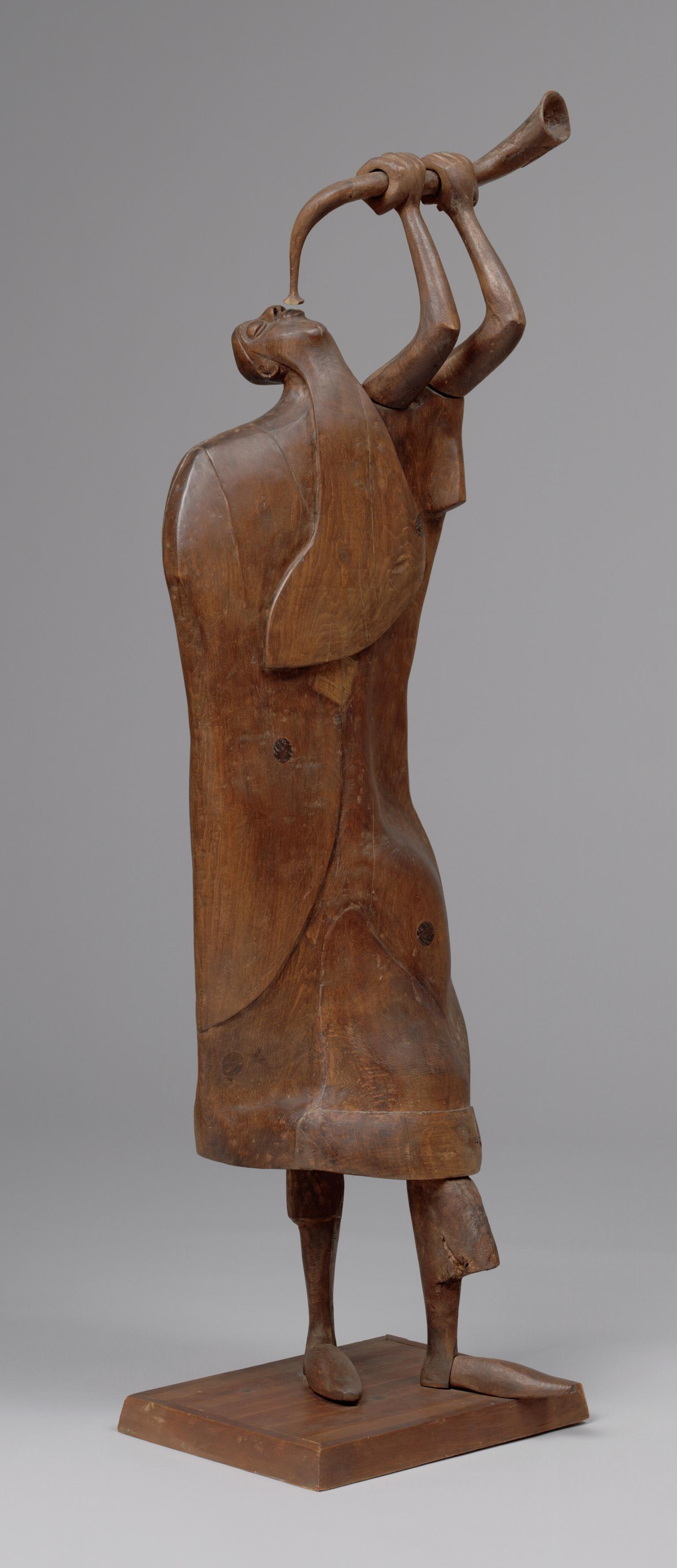 Wood carving of man blowing shofar.