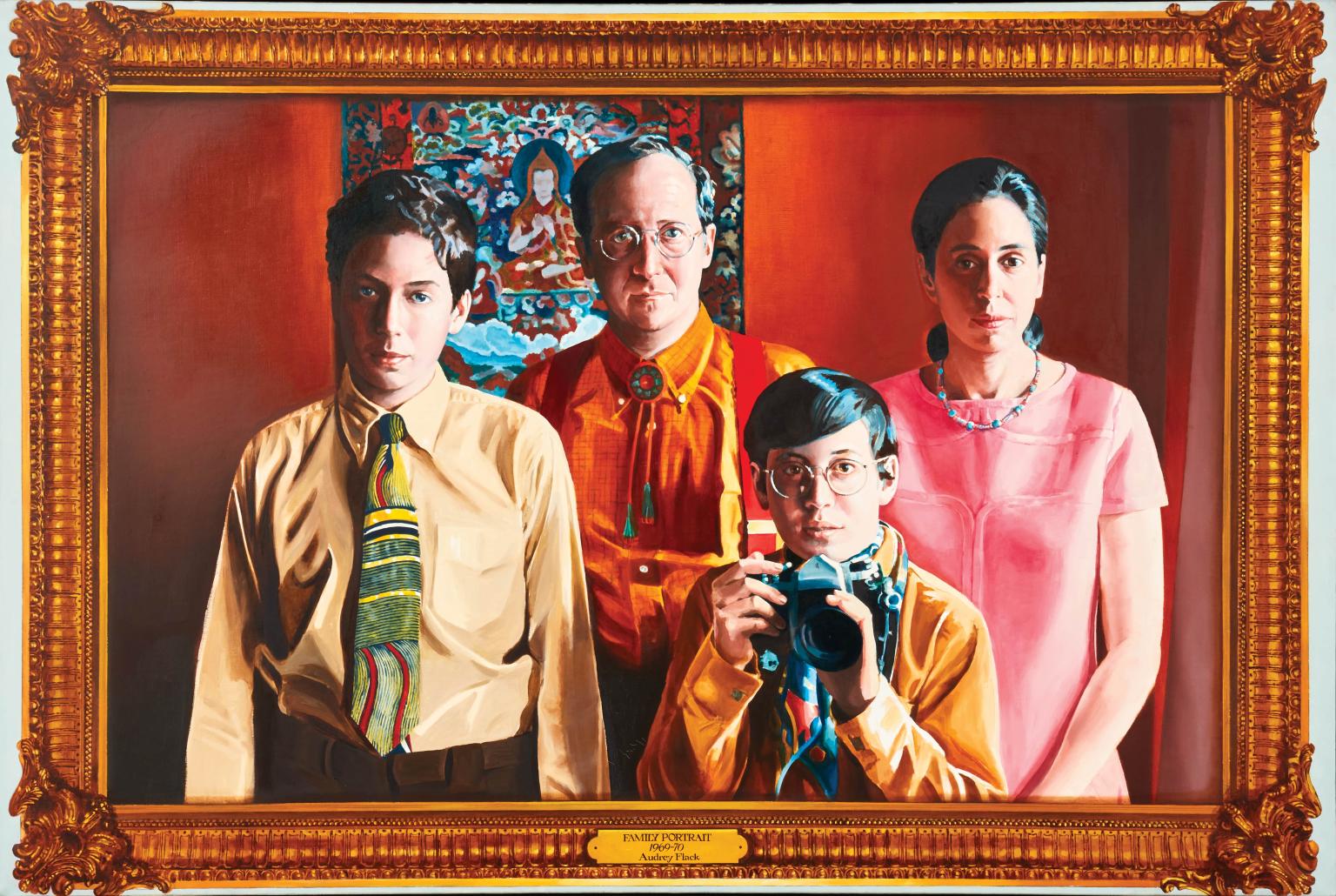 Photorealist painting of woman, man, and two young boys, one of whom holds camera, standing in front of a picture of a meditating god and looking at the viewer. 