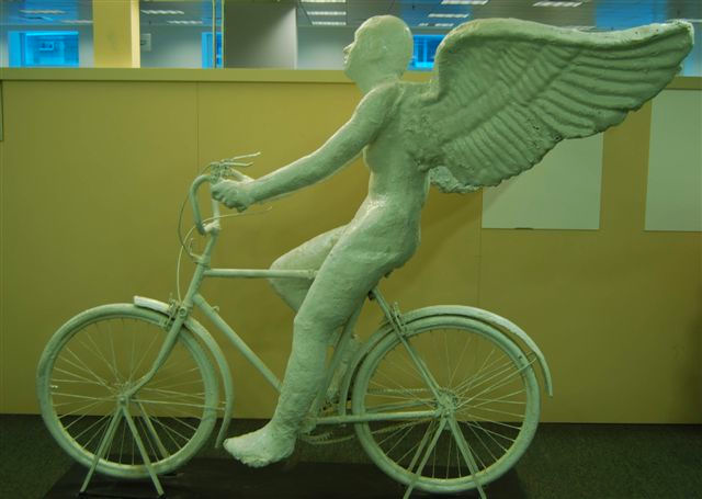 Sculpture of winged figure on bicycle.