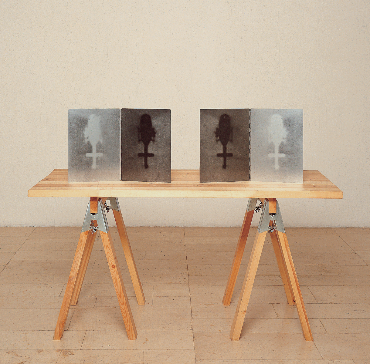 Sawhorse table with four images of a helicopter from a bird's-eye view propped up on it. 