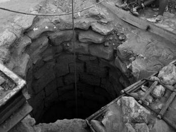 Well at Beersheba Photograph of stone well with rope system and two figures standing on the side.