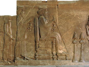 Relief of man sitting on throne with figures standing on either side.