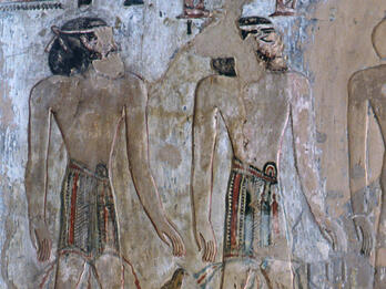 Mural of two figures looking at each other under hieroglyphs.