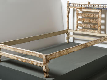 Bed frame decorated with ivory inlay with elaborate carving on headboard.