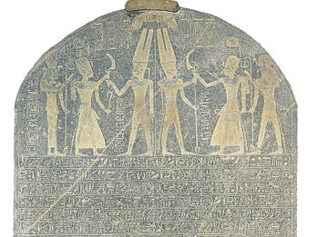 Stela of Merneptah Stone with rounded top with drawing of six figures wielding weapons and Egyptian hieroglyphic writing in rows.