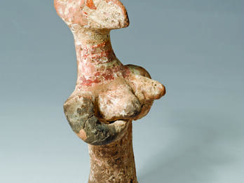 Terra-cotta figurine with enlarged head and breasts.