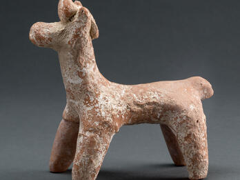 Terra-cotta figurine of horse with ornament on head.