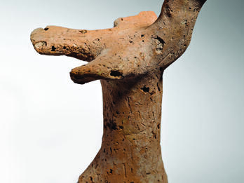 Terra-cotta bird figurine with outstretched wings on pillar.