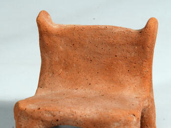 Terra-cotta chair with four short legs.