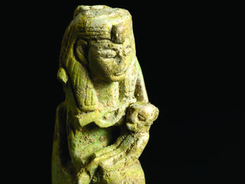 Amulet Depicting Isis Holding Horus Faience amulet with Egyptian goddess wearing headdress sitting on a throne and holding a child.