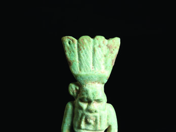 Faience Amulet Depicting Bes Frontal and back faience amulet of figure who is nude with feathered headdress and a grotesque face and beard.