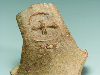 Ceramic handle with impression of stylized two-winged figure and Hebrew inscription.