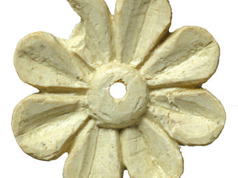 Ivory carving in shape of an eight-petaled flower with small hole in center.