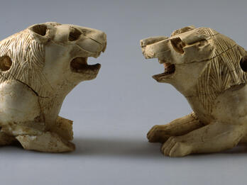 Two ivory lion figurines with open mouths and small holes throughout.