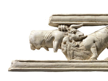Ivory carving of a sphinx amid lotus flowers.
