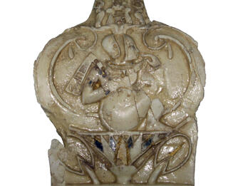 Carved leaf-shaped ivory relief of child sitting on a lotus flower.