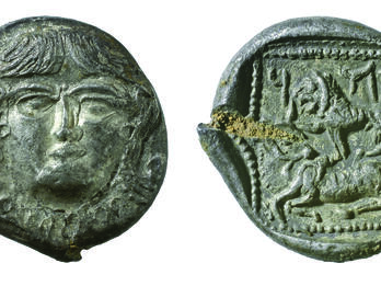 Front and back of coin, with image of face on front of coin and lion, bovine, and Hebrew inscription on back.
