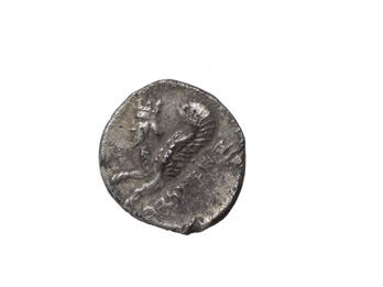 Coin with image of winged creature with human head, beard, and horns and Hebrew inscription.