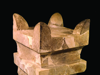Square limestone altar with horns at four upper corners and recessed band below offering surface.