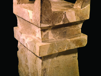 Square limestone altar with horns at four upper corners and recessed band below offering surface.