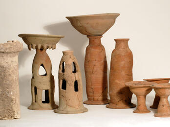 Ritual containers including stone altar, two offering bowls on tall bases, four chalices, and two stands with cylindrical bases. 