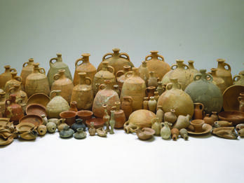 Collection of many ceramic containers including bowls, bottles, decanters, jugs, and oil lamps.