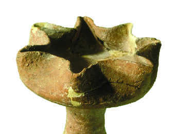 Ceramic oil lamp with seven spouts on a pedestal.