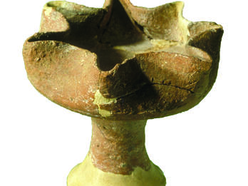 Ceramic oil lamp with seven spouts on a pedestal.