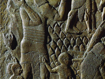 Wall relief of adult male walking with two boys dressed in tunics and caps. 