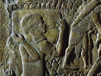 Wall relief of adult male walking with two boys dressed in tunics and caps. 