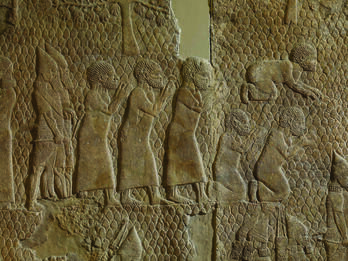 Wall relief showing six men dressed in tunics, one prostrate and two kneeling, with two bearded soldiers behind them.