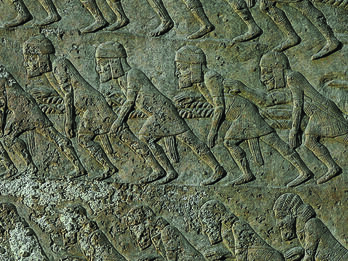 Wall relief showing workers wearing tunics, caps, and sashes, harnessed by shoulder straps to ropes and leaning forward. 