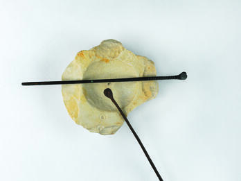 Limestone bowl and two small bronze spatulas resting on it.
