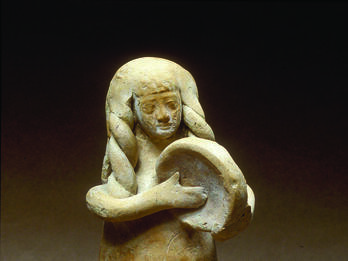 Terra-cotta figurine of women with long hair playing frame drum. 