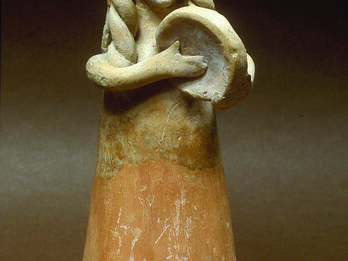 Terra-cotta figurine of women with long hair playing frame drum. 