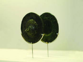 Pair of round bronze cymbals set on a modern wire display frame. 