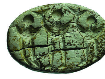 Seal depicting three people with raised arms holding up T-shaped objects.