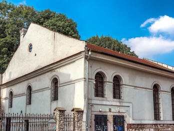 Photograph of building exterior with curved windows and gated courtyard to left.