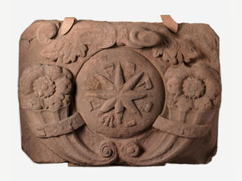 Stone with carving of star in center and flowers on either side.